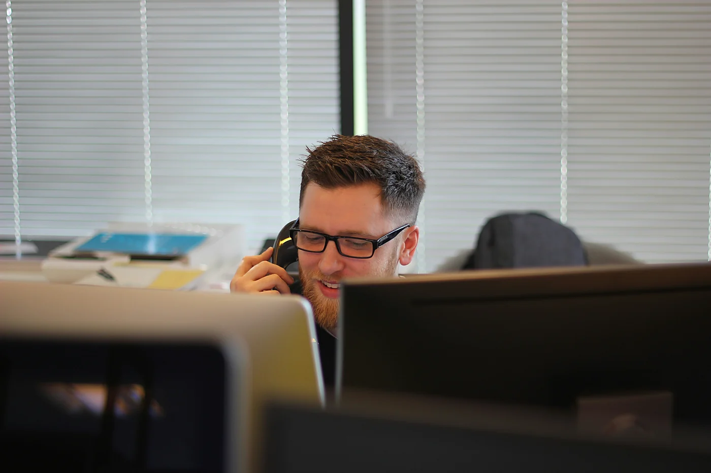 An agent in glasses taking a call at his desk